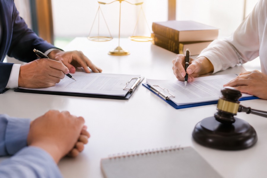 Two people signing documents at a desk