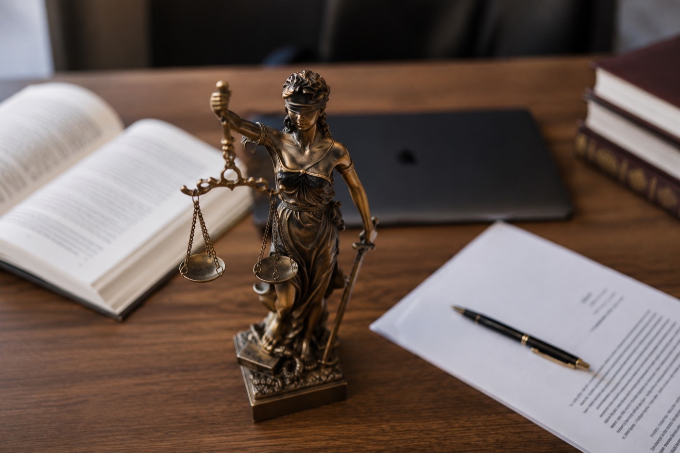 Statue of Lady Justice on an attorney's desk beside signed documents